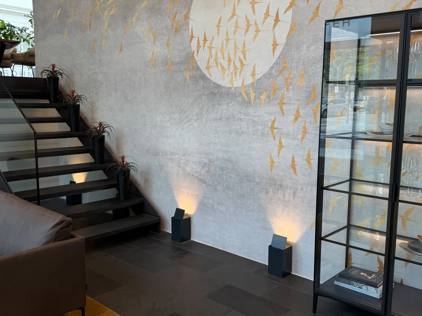 Wandbild mit goldenen Vögeln, Treppe und beleuchtete Vitrine